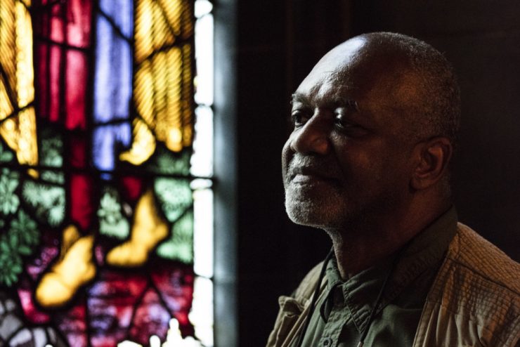 Close-up of artist Kerry James Marshall with detail of stained glass window to his right