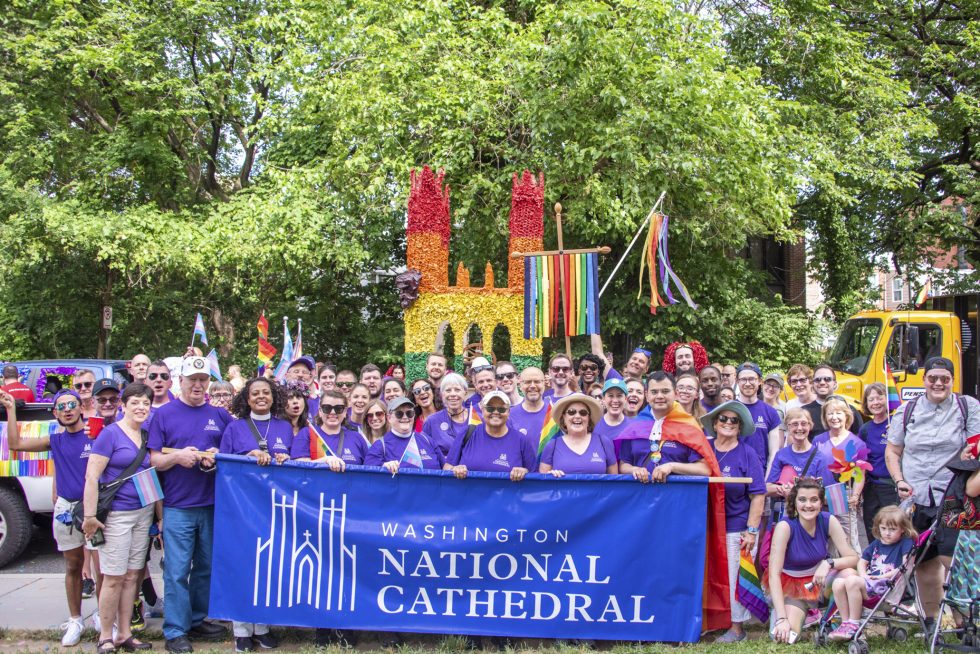 Outdoor group photo of Cathedral Congregation at Pride event with Cathedral banner and adorned cross