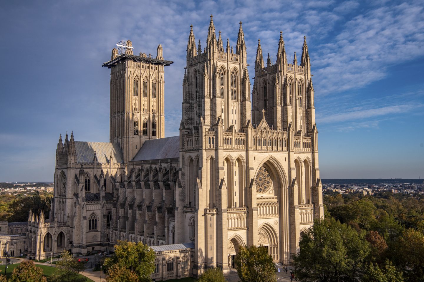 Exterior shot of the West facade and North side of the Cathedral, with leafy trees and blue skies