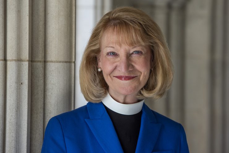 Headshot of Cathedral Provost, smiling and wearing a blue jacket over priestly vestment
