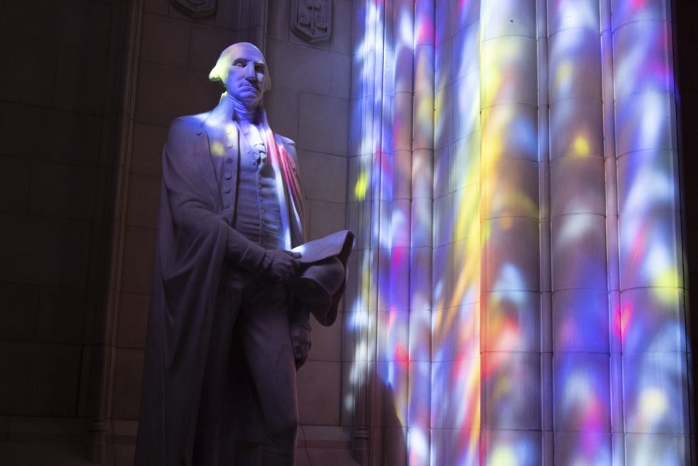 Colorful light filtered through the Cathedral's stained glass windows over the statue of George Washington