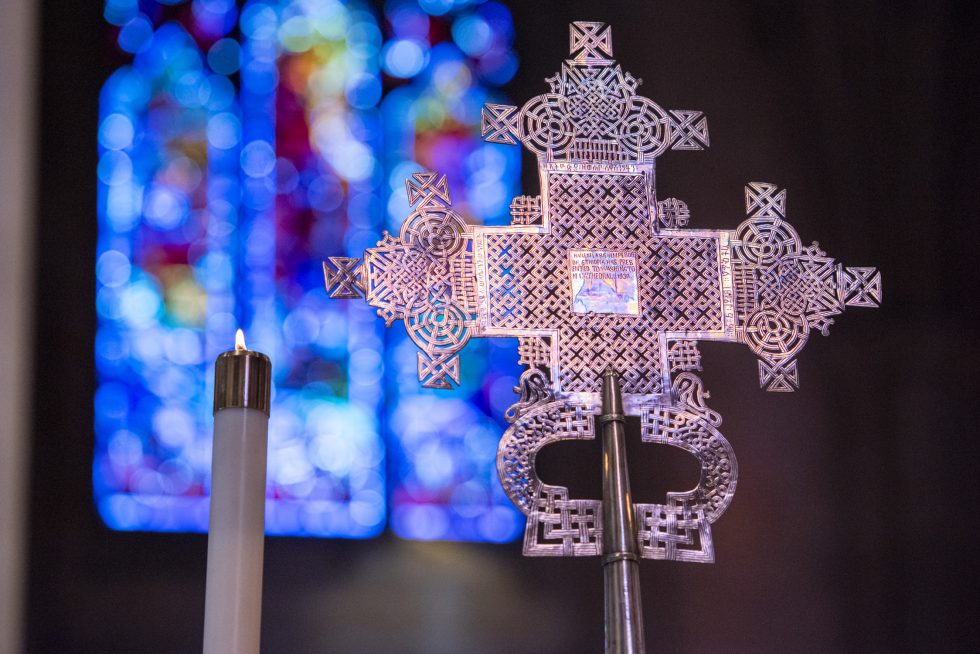 Cross and candle with stained glass window in the background