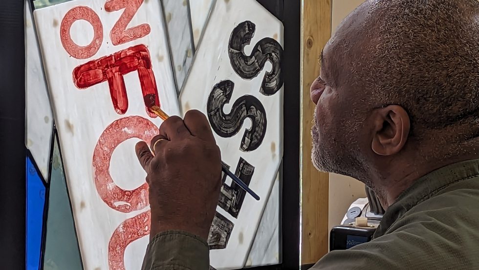 Close-up of the artist painting letters on glass 
