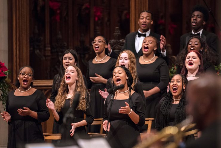 A choir dressed in formal black attire sings a hymn.