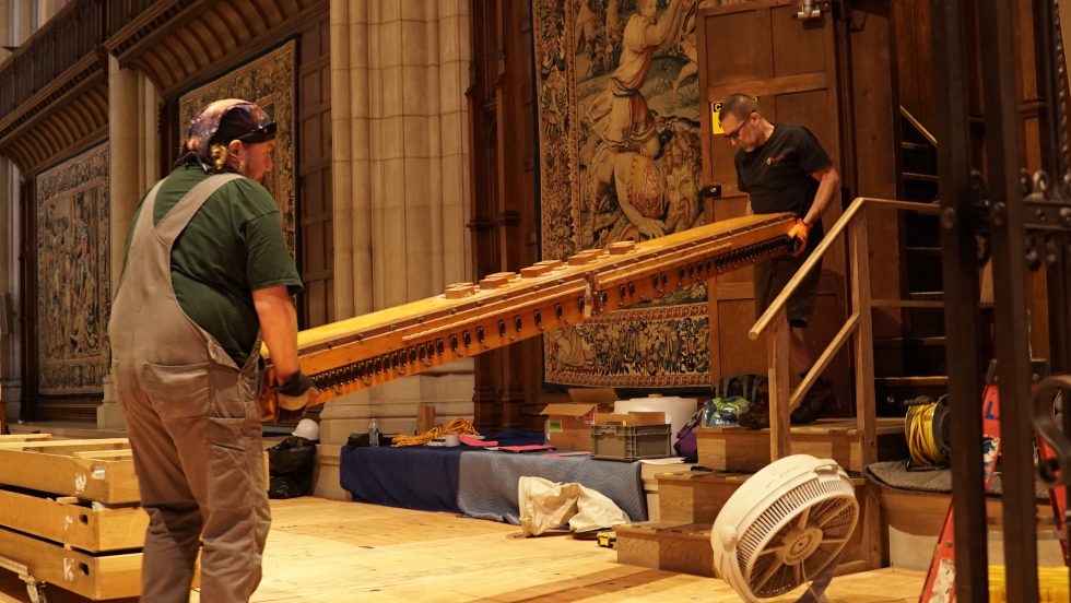 workers carry organ pipes in a church