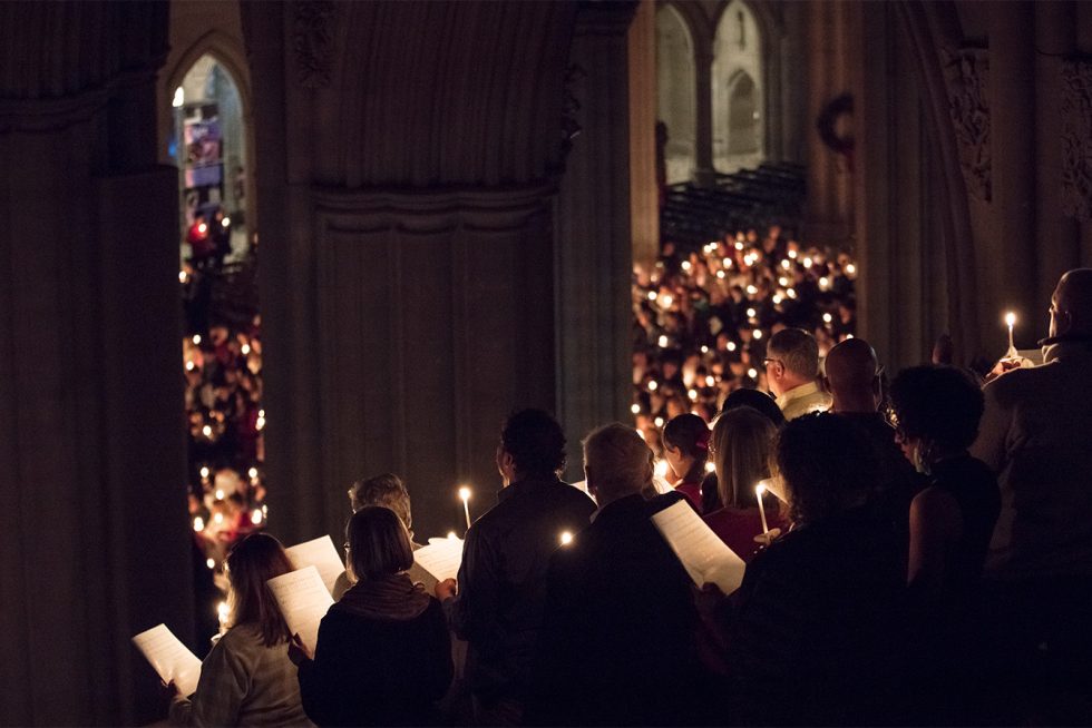 Service attendees hold candles during a hymn in the darkness of the nave.