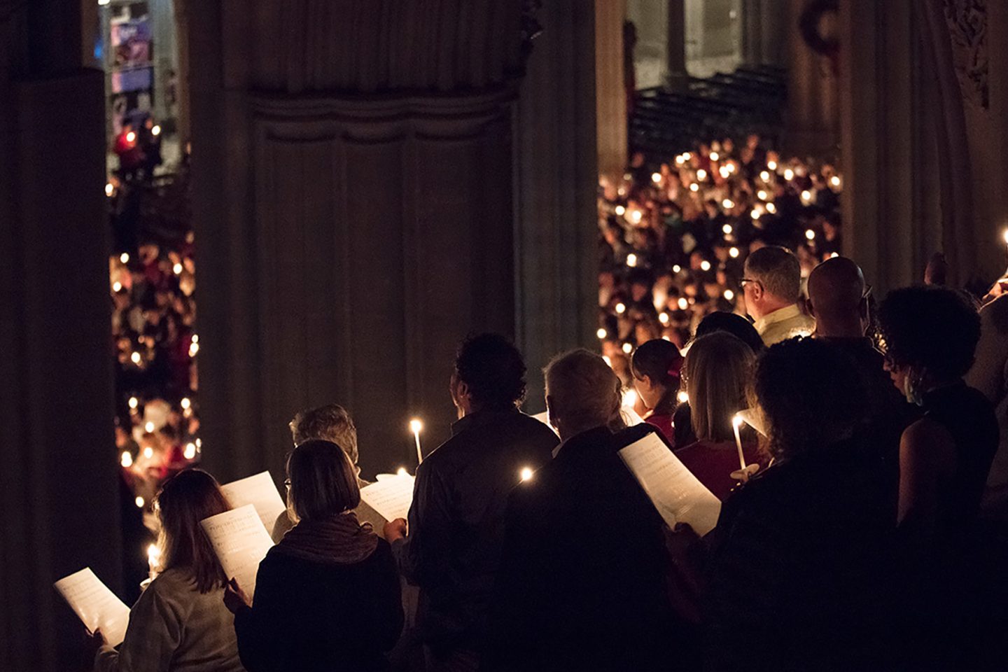 Service attendees hold candles during a hymn in the darkness of the nave.
