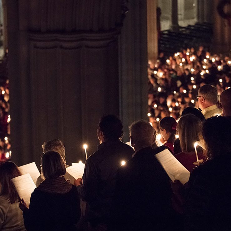 Service attendees hold candles during a hymn in the darkness of the nave.