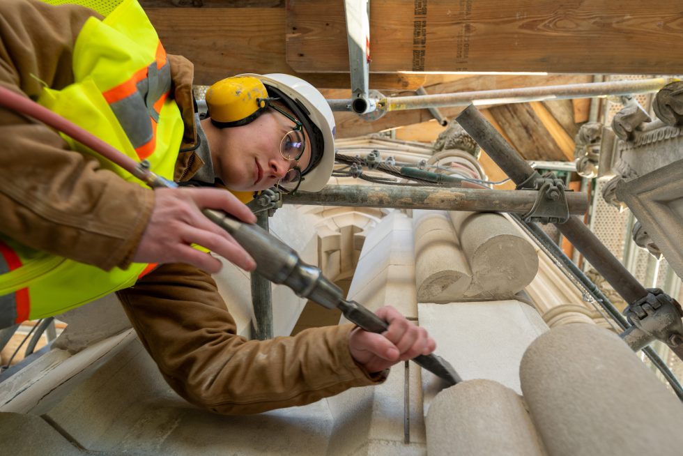 A stone mason works on a Cathedral