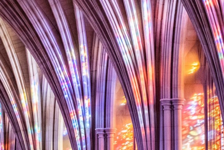 Cathedral architecture detail with colorful lights cast through stained glass windows